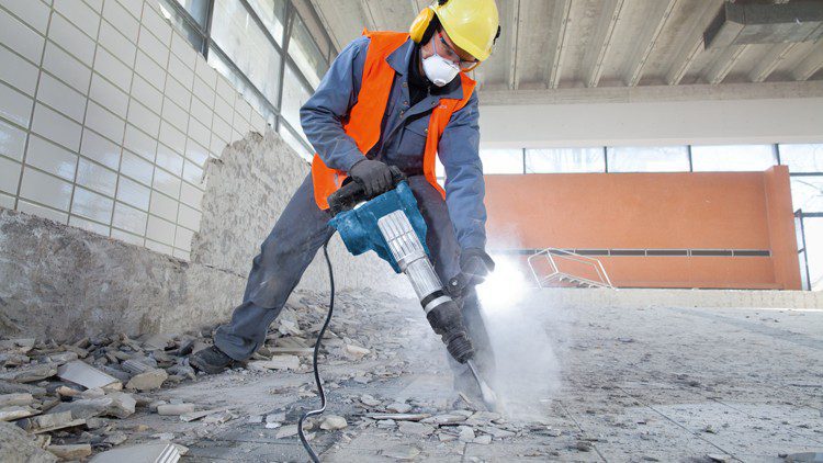 Trabalhador utilizando martelo pneumático, sendo parte dos efeitos da vibração ocupacional.