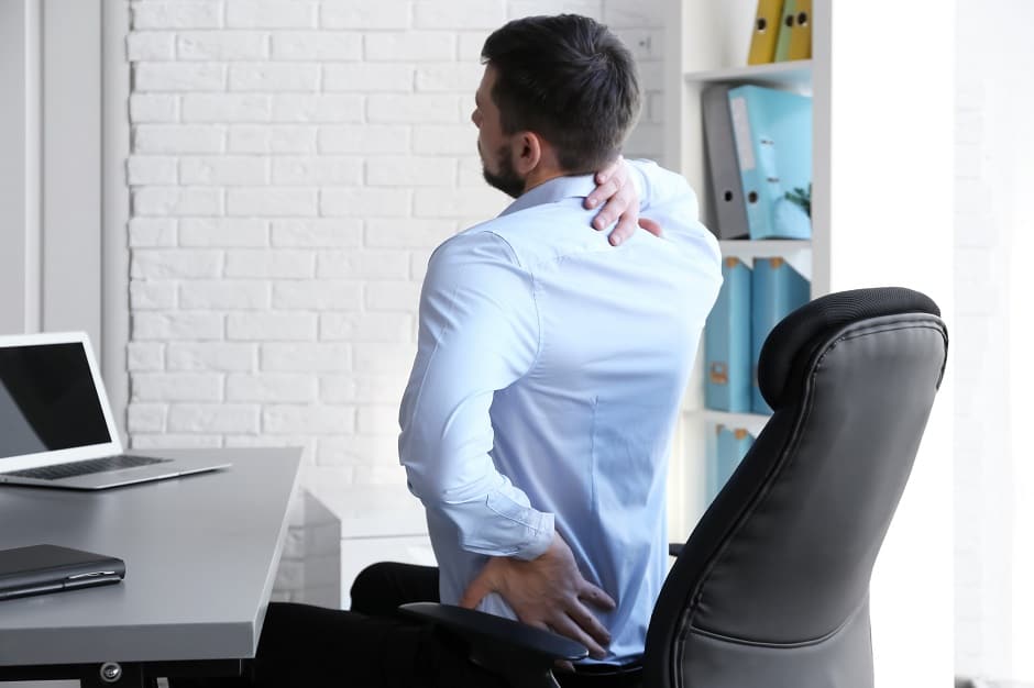 Trabalhador sentindo dor devido à falta de ergonomia, fazendo parte do grupo de doenças ocupacionais.